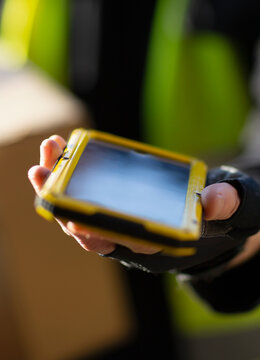 Close up courier with smart phone requesting signature for delivery