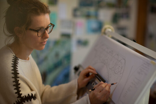 Focused female architect working at drafting table