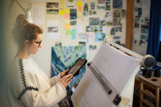 Female architect video chatting at drafting table in home office