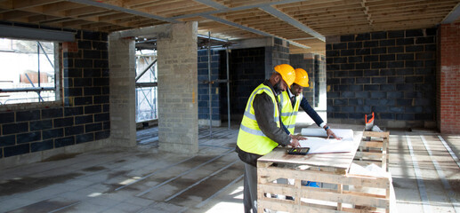Engineer and foreman reviewing blueprints at construction site