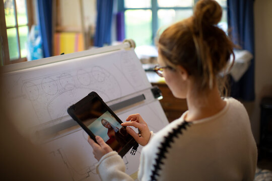 Female architect video chatting and working at drafting table