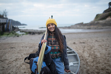 Portrait happy young woman with canoe and oars on beach