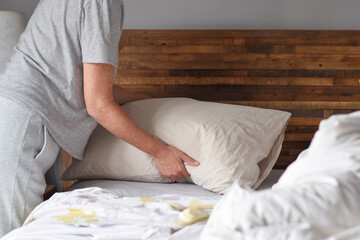 Woman is adjusting pillow while making the bed