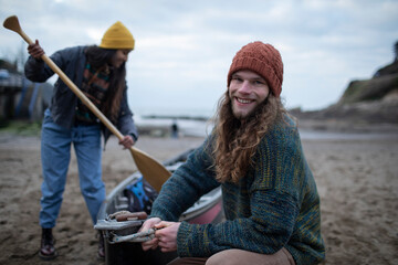 Portrait carefree young couple preparing canoe on beach