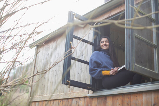 Happy young woman in tiny cabin rental window