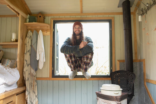 Portrait happy young man in pajamas in tiny cabin window