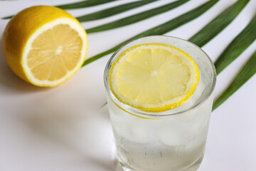 A glass of water with ice cubes and lemon on the table close-up. Summer refreshments and detox...