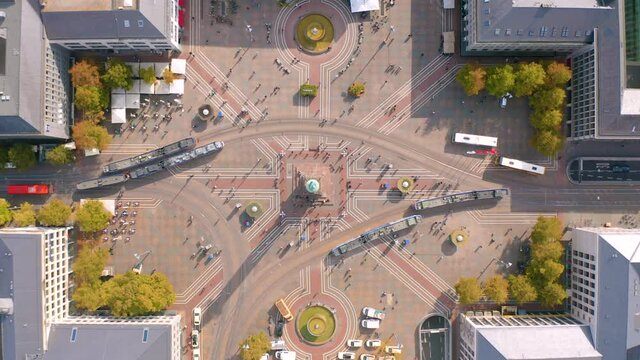 Aerial view directly above the square with dense traffic of public transport (tram, bus) arriving and departing; crowd of people (passengers) moving around. Luisenplatz in Darmstadt, Germany