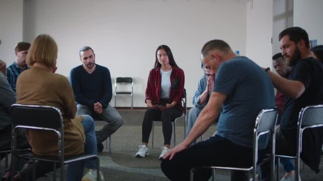 People supporting upset man during group meeting