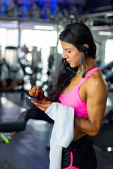 Mid age woman using a smartphone after exercise in the gym