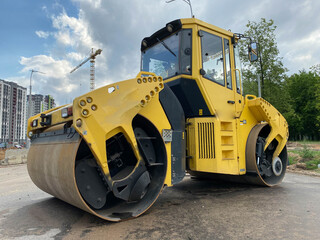 Fototapeta premium Yellow powerful large new modern road roller for asphalt paving and road repair at construction site. Construction machinery