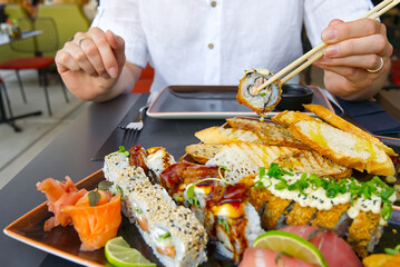 eating sushi with chopsticks at sushi restaurant woman holding sushi roll with wooden chopsticks