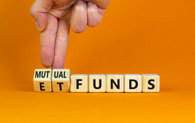 Mutual funds vs ETF symbol. Businessman turns cubes and changes words 'ETF, Exchange-Traded Fund' to 'Mutual funds. Beautiful orange background, copy space. Business and ETF vs mutual funds concept.