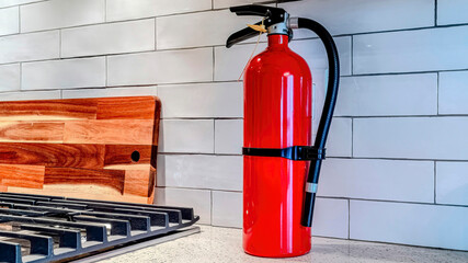 Pano Bright red fire extinguisher against white tile backsplash inside home kitchen