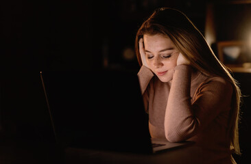 Young depressed woman sitting in her room in the dark. Studies l