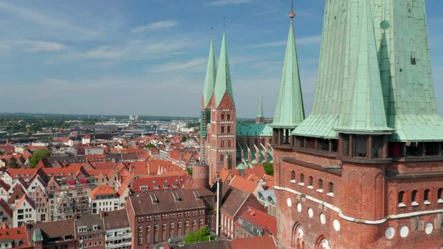 Slide and pan reveal of medieval city centre behind St. Peters church tower. Brick gothic buildings. Luebeck, Schleswig-Holstein, Germany
