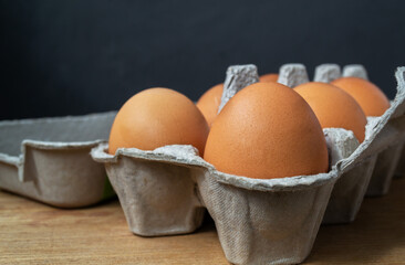 Egg carton. A full tray of brown eggs on a dark background in a standard package