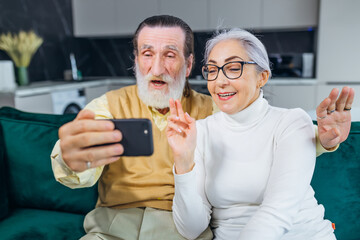 Happy mature senior couple taking selfie looking at smartphone,