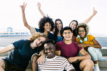 Portrait of diverse college friends sitting on city stairs - Happy multiracial group of young...