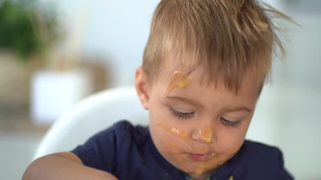 Baby boy eating porridge with dirty face
