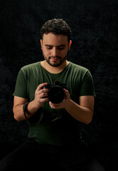 retrato de joven fotografo sosteniendo una camara  en un fondo negro con textura