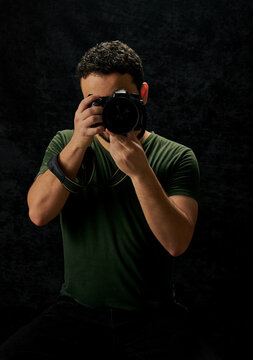 retrato de joven fotografo sosteniendo una camara  en un fondo negro con textura