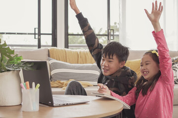 Mixed Asian children making video calling with laptop at home, using zoom online virtual class ,...