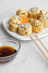 elegant and simple decoration of a plate with sushi rolls, carrot, chopsticks and container with soy sauce ready to be served, healthy food in studio, texture detail