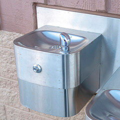 Square Shiny metal drinking fountain for children and adults mounted on building wall