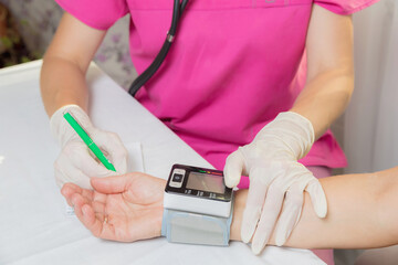 A girl doctor measures the blood pressure of an adult woman. The patient asked for help with high blood pressure. Health and medicine concept. - obrazy, fototapety, plakaty