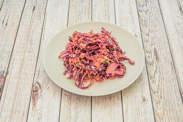 Purple cabbage salad with mayonnaise, vinegar and chopped chives on a white table.