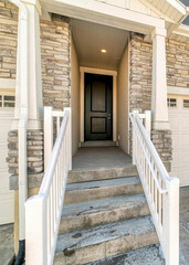 Vertical Townhouse entrance with concrete stairs leading to front door under a portico