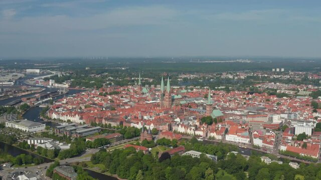 Aerial panoramic view of medieval city centre. Fly around historic brick buildings, churches with tall towers. Luebeck, Schleswig-Holstein, Germany