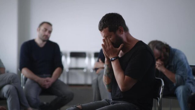 Desperate man crying during group meeting for addicts