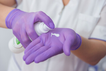 Obraz premium Cosmetologist squeezing out a tube of cream on her hand with gloves
