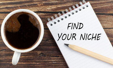 FIND YOUR NICHE text on notebook with coffee on wooden background