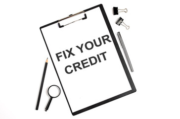 On a white background magnifier, a pen and a sheet of paper with the text FIX YOUR CREDIT , . Business concept