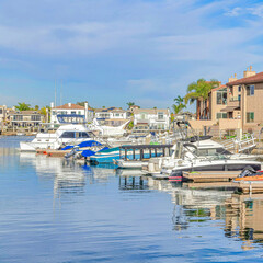 Square Boats docked at the harbour with waterfront homes in Huntington Beach California