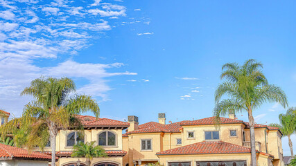 Pano Blue sky with clouds with home and palm trees in Huntington Beach California