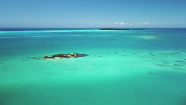 Aerial ascending shot of turquoise atoll with Ilot Brosse in the background, New Caledonia