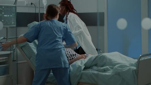 Multi ethnic medical staff running to help ill patient with oxygen tube and heavy breathing problems. African american doctor preparing from reanimation at intensive care unit