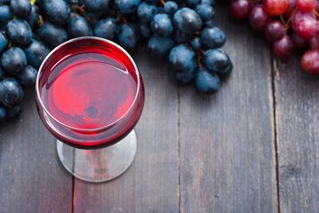 glass of red wine and grapes on black wooden table background
