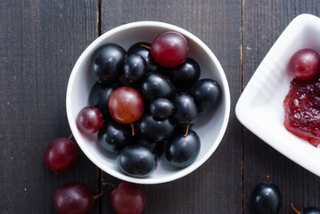grape jelly and red grapes on black wood table