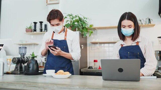 Asian Barista couple enjoy doing digital marketing in cafe restaurant.