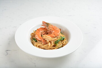 mixed seafood pasta with big tiger prawn, scallop shell clam and muscle in alio olio salted egg yolk paste sauce in white background western halal cuisine 