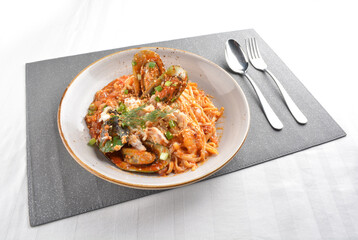mixed seafood pasta with big tiger prawn, scallop shell clam and muscle in spicy chilli crab sauce or tomato paste sauce in white background western halal cuisine 