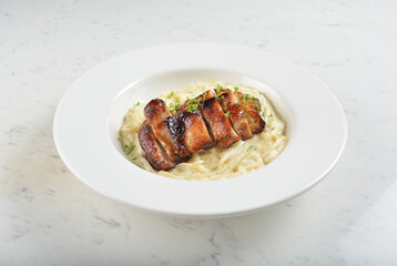 carbonara pasta with japanese teriyaki bbq chicken chop in creamy cheese white sauce in white background western halal menu