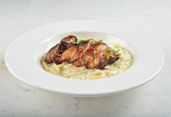 carbonara pasta with japanese teriyaki bbq chicken chop in creamy cheese white sauce in white background western halal menu