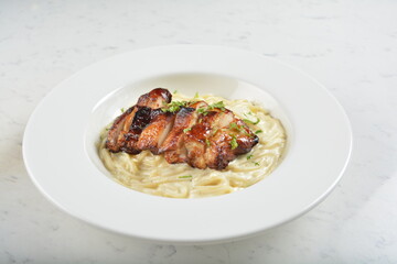 carbonara pasta with japanese teriyaki bbq chicken chop in creamy cheese white sauce in white background western halal menu