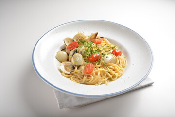 olive oil mixed seafood clam shell pasta in aglio olio style and cherry tomato in white background western halal menu